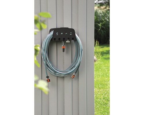 Trädgårdsslang med slanghållare monterad på en vägg