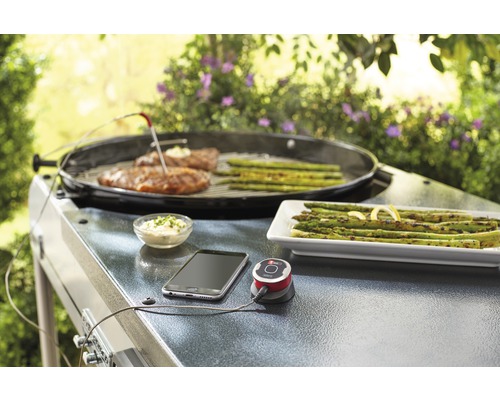 Grillscen med kött, sparris, termometer, smartphone och dippsås