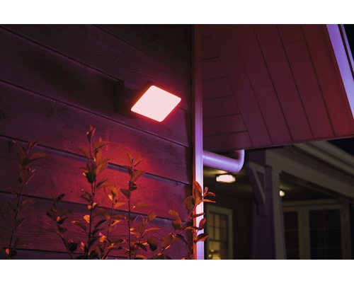 Fyrkantig LED utomhusvägglampa på hus med växtlighet