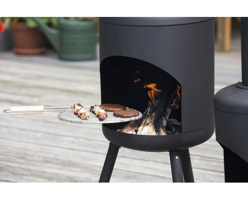 Eldstad med grillgaller, lastad med köttspett och hamburgare, i drift med brinnande ved