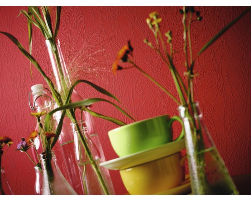 Dekorativt stilleben med blommor i flaskor och staplade koppar.