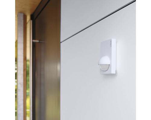 Utanpåliggande rörelsedetektor för utomhusbruk monterad på en vägg.