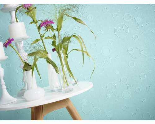 Ljusblå tapet med cirkelmönster bakom en bordsdekoration.