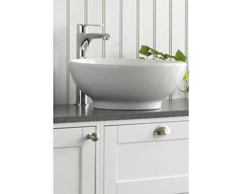 Keramisk tvättställsskål med blandare på ett vitt underskåp