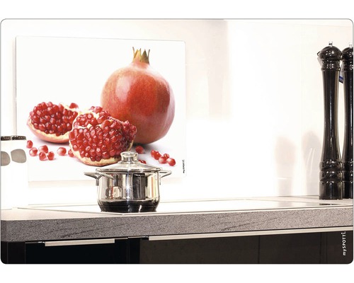 Köksscen med stänkskydd med granatäpplemotiv bakom en kastrull