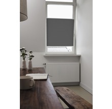 Interiörbild av ett rum med en grå plisségardin i fönstret, ett träbord och en sittbänk