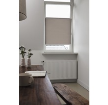 Miljöbild med plisségardin vid fönstret, bord, sittbänk och element