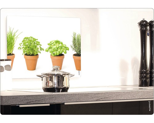 Köksscen med kastrull på spis och örtbild som stänkskydd