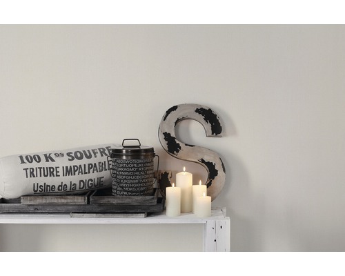 Dekorativ scen med kudde, burk, bokstav och ljus på en vit hylla