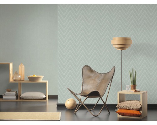 Vardagsrum med mönstrad tapet, fåtölj och sidobord