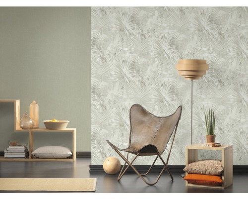 Vardagsrum med mönstrad tapet, fåtölj och hyllor.