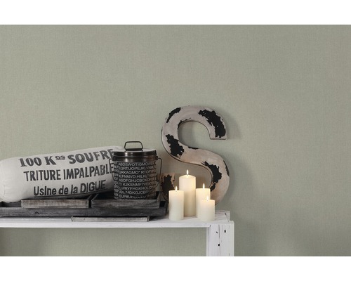 Dekorativ scen med textilpåse, plåthink, dekorativ bokstav och ljus på en vit hylla