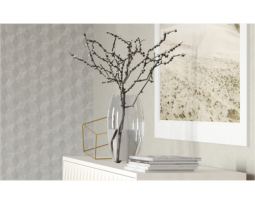 Dekorativ scen med vas, grenar, geometrisk dekoration och bildram på en skänk framför en mönstrad tapet