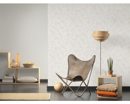 Ljust vardagsrum med mönstrad tapet, fåtölj och trähyllor