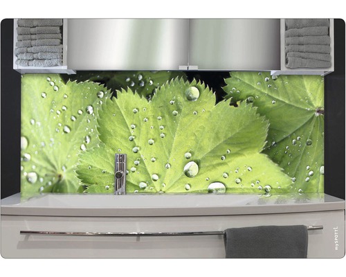 Badrum med handfat, handdukar och väggpanel med löv och vattendroppar