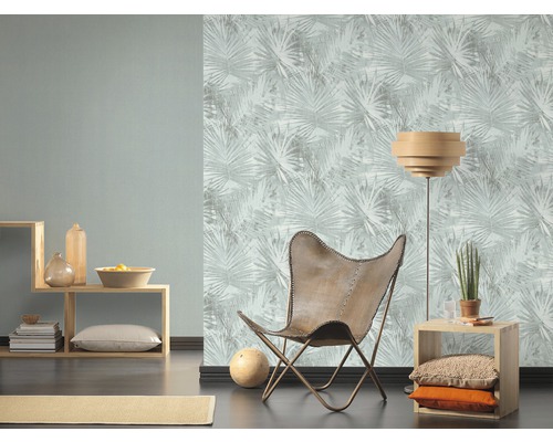 Vardagsrum med fåtölj, golvlampa och tapet med bladmönster