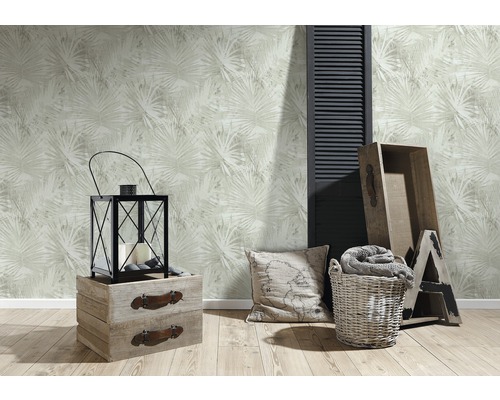 Dekorativt vardagsrum med blommönstrad tapet, lykta, kudde, trälådor och dekorationer