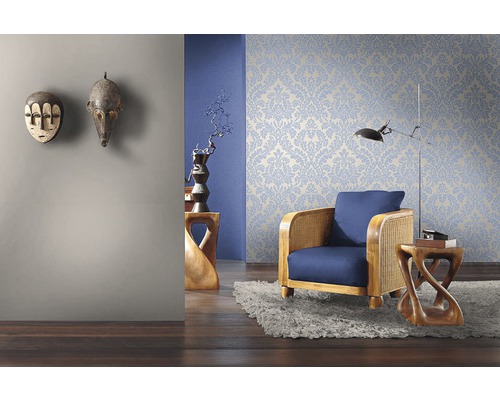 Vardagsrum med blommönstrad tapet, fåtölj och dekorativa trämasker