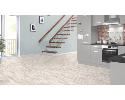 Ljust rum med laminatgolv, trappa och grått inbyggnadskök