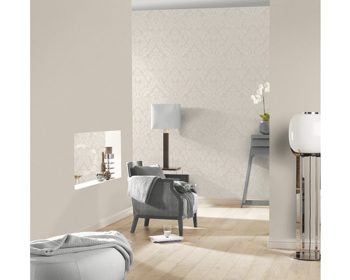 Ljust vardagsrum med mönstrad tapet, fåtölj och lampa