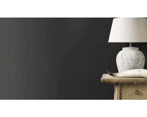 Dekorativ scen med lampa, horn och träbyrå mot en mörk vägg.