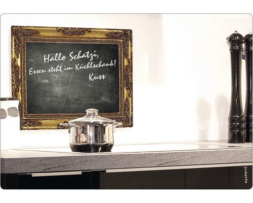 Svart tavla med guldfärgad ram, kastrull på spishäll