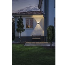 Exteriörvy av ett hus med trädgård, bänk och upplyst fasad