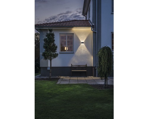 Exteriörvy av ett hus med trädgård, bänk och upplyst fasad