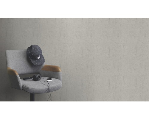 Scen med en grå fåtölj, en keps, hörlurar och en musikspelare framför en grå vägg.