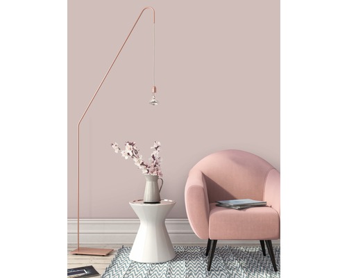 Dekorativ inredning med golvlampa, sidobord med blomvas och fåtölj.