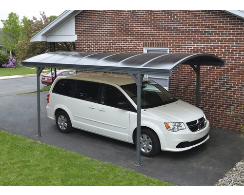 Övertäckt parkeringsplats med en parkerad bil framför ett hus