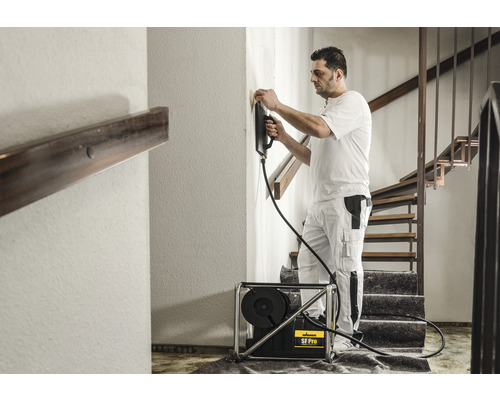 En man använder ett färgspraysystem i ett trapphus för att måla väggarna.