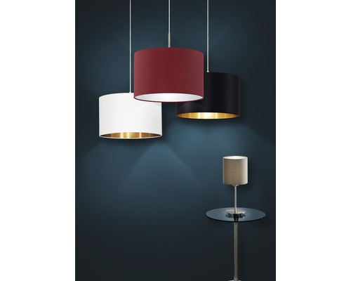 Tre textilupphängda lampor med olika lampskärmsfärger och en bordslampa på ett sidobord.