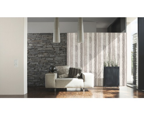 Vardagsrum med fåtölj, stenvägg och dekorativ rumsavdelare