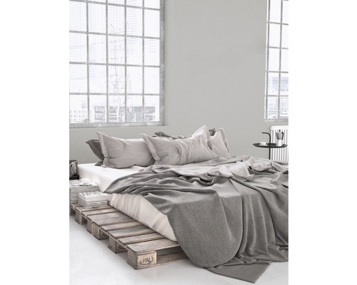 Sovrum med sängram av träpallar, sängkläder och kuddar