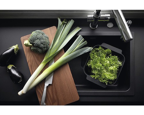 Grönsaker som aubergine, broccoli och purjolök på en skärbräda bredvid en diskho