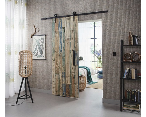 Rum med skjutdörr i trä, golvlampa och bokhylla