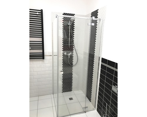 Duschkabin med glasvägg och svart radiator i badrummet.