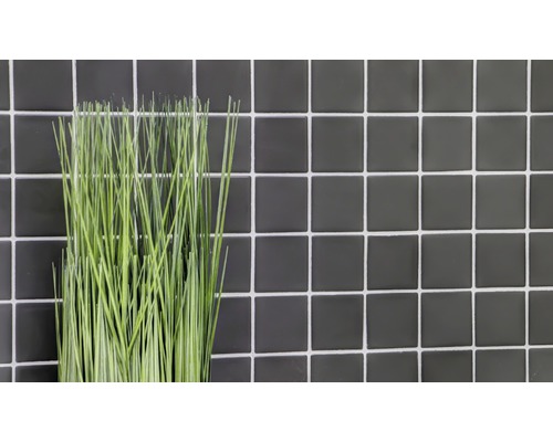 Dekorativ konstgjord växt framför en vägg av kakel