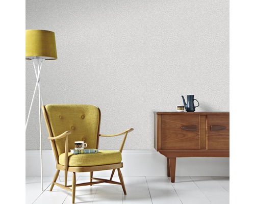 Inredningsexempel med mönstrad tapet, fåtölj, golvlampa och byrå