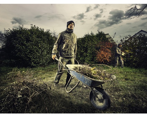 Man skjuter skottkärra med trädgårdsavfall i trädgården