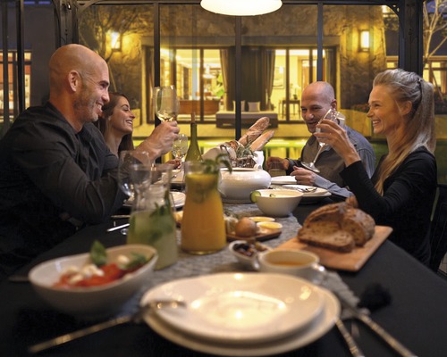 En grupp människor sitter vid ett dukat bord och njuter av en måltid i en ljus och inbjudande atmosfär.