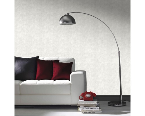 Vardagsrum med vit soffa, kuddar, golvlampa och mönstrad tapet