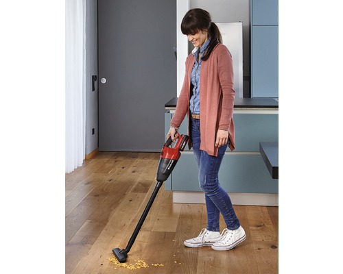 En kvinna använder en Einhell sladdlös handdammsugare på ett trägolv i ett kök.