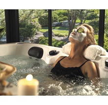 Kvinna som kopplar av med ansiktsmask och gurkskivor i en bubbelpool i trädgården.