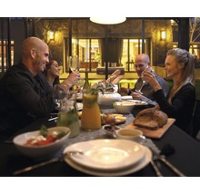 En grupp människor sitter vid ett dukat bord under en middag
