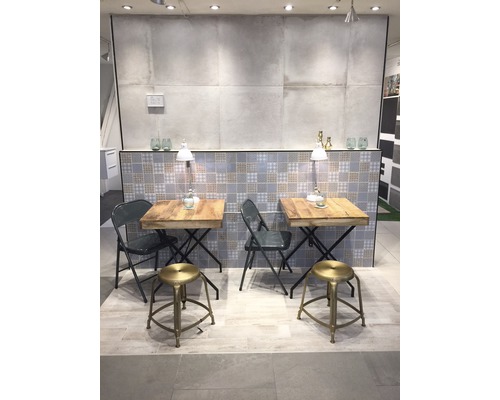 Visningsrum med två bord och sittplatser, kakelbakgrund och belysning.