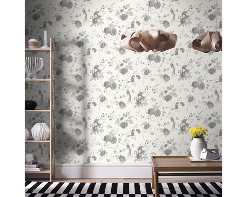 Dekorativt vardagsrum med blommig tapet, trähylla, träbord och hänglampor