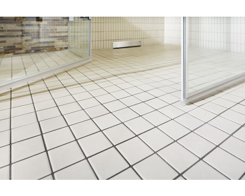 Badrum med fyrkantiga golvplattor och duschkabin