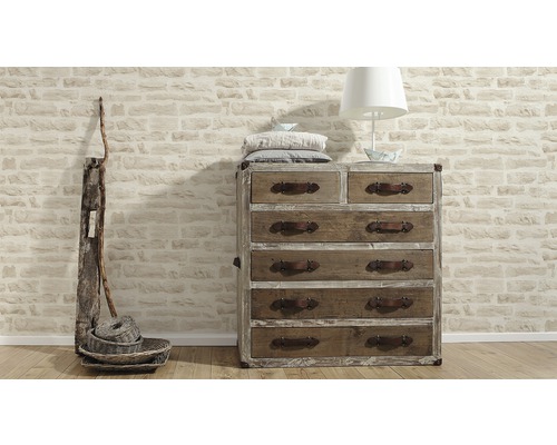 Byrå med lådor, lampa, kuddar och dekoration framför en stenmur